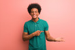 © Asier - Young african american man over a pink wall holding something with hand