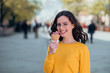© bnenin - Portrait of a casual smiling young woman eating ice cream in the springtime in the town street.