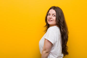 Wall Mural - Young curvy plus size woman looks aside smiling, cheerful and pleasant.