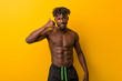© Asier - Young black man shirtless wearing swimsuit showing a mobile phone call gesture with fingers.