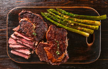 Wall Mural - tasty and juicy steak and asparagus half fried in a frying pan and sprinkled with grated Parmesan cheese