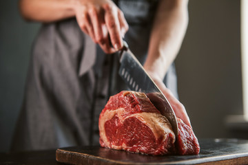 cook cuts raw meat for steaks