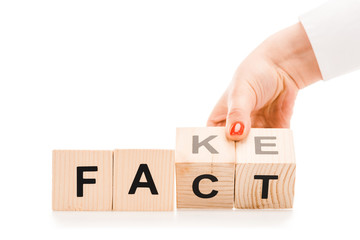 partial view of woman holding wooden blocks with fact or fake words isolated on white