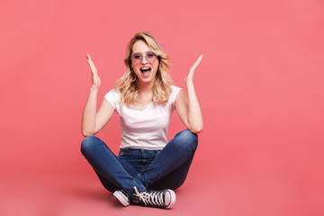 Sticker - Portrait of beautiful blond woman 20s wearing vintage sunglasses laughing while sitting on floor with legs crossed