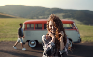 Wall Mural - A young girl on a roadtrip through countryside, standing by a minivan.