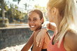 Two laughing young women taking a break from exercising outside