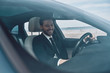 © gstockstudio - So happy! Handsome young man in full suit smiling while driving a car
