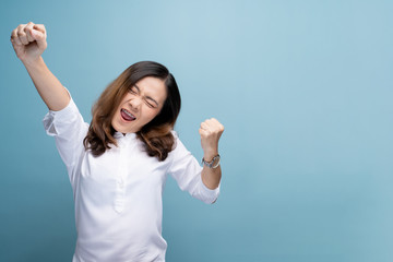 Happy woman make winning gesture isolated over blue background