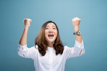 Happy woman make winning gesture isolated over blue background