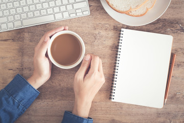Wall Mural - top view of business hand on desk have coffee, toast, notebook blank and pencil on
