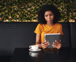 © StratfordProductions - Serious young woman looking at digital tablet in cafe
