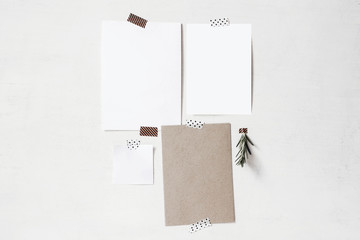 Set of blank greeting cards, note paper mockups. Empty sheets of white and kraft paper and rosemary herb branch taped on the old white wall. Design mood board. Memory concept.
