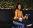 © StratfordProductions - Happy young woman sitting in cafe holding digital tablet