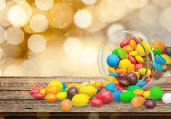 Wall Mural - Colorful candies sweets falling out of a glass jar, composition isolated over the white background