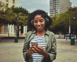 Wall Mural - Woman using mobile phone while listening music on headphone