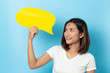© suriya - Portrait of young girl holding a empty yellow speech bubble isolated on blue background