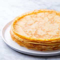 Wall Mural - Crepes, thin pancakes, blini on a white plate. Marble background. Close up.