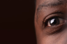 Close Up Of African American Eye On Dark Brown Background