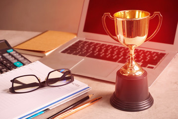 Wall Mural - trophy and laptop and blank book on working table, win concept.