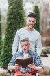 A man is carrying his father, they are having fun and they are laughing while reading a book! Time for reading!