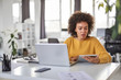 © nenadaksic - Serious mixed race businesswoman dressed  casual sitting in office and using tablet.