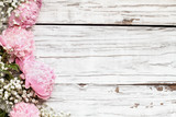 Pink Peonies and Baby's Breath flowers with pensil and blank note book over a white rustic wood table background with copy space for your text. Flat lay.