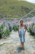 © Seth Mourra/Stocksy - Woman wading in a stream near a field of lupins