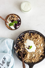 Wall Mural - Oatmeal crumble in cast iron pan with fresh blueberry and natural yogurt. Healthy food concept. 