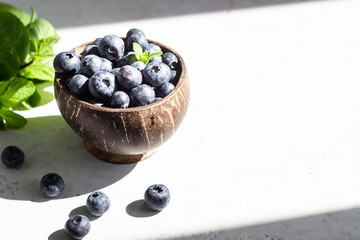 Wall Mural - Wooden bowl of fresh blueberries on light grey stone table. Healthy organic seasonal fruit background. 