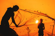© Wizemark/Stocksy - Anonymous, unrecognizable, silhouetted fisherman on the beach shore using fishing net during beautiful, golden sunset