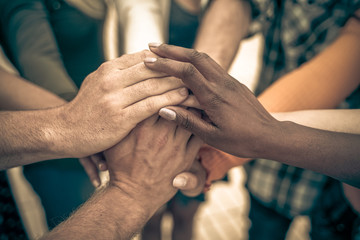 young people putting their hands together. friends with stack of hands showing unity and teamwork – 