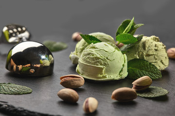 Wall Mural - Gourmet pistachio ice cream served on a stone slate over a black background.