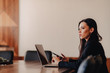 © pressahotkey - Young attractive emotional girl in business-style clothes sitting at a desk on a laptop and phone in the office or auditorium