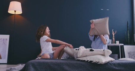 mommy and kid daughter having pillow fight together, young babysitter nanny playing funny game with 