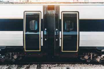 View of the junction of two cars of a modern suburban train waiting on the platform in Portugal; the area of joining of two wagons of a contemporary high-speed train with black and white body