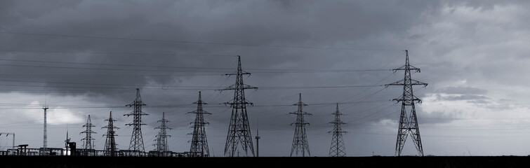  Power station in the steppe.Power lines and sky with clouds.High voltage power lines.Field and aerial lines, silhouettes at dusk.Electric power industry and nature concept.In black and white.