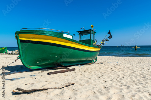 Small, green fishing boat resting on shore. Beach near Gdynia, Poland