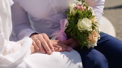 Wall Mural - Groom holding bride’s hand and bouquet in sunlight