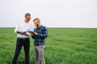 © Serhii - Two farmer standing in a wheat field and looking at tablet, they are examining corp. Young handsome agronomist. Agribusiness concept. agricultural engineer standing in a wheat field