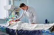 Intensive care caucasian doctor examines intubated critical stance patient in intensive care department