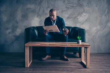 Wall Mural - Portrait of his he nice stylish classy chic imposing elegant attractive guy professional top manager company banker sitting on couch reading paper at workplace station gray concrete wall