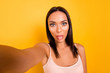Close up photo beautiful amazing she her lady make take selfies instagram followers tongue out mouth naughty childish mood wear casual pastel tank-top clothes isolated yellow bright background