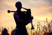 A Young Modern Man Plays Musical Bagpipes Outside. Siluet