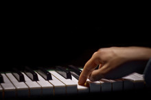 One Male Hand On The Piano. The Palm Lies On The Keys And Plays The Keyboard Instrument In The Music School. Student Learns To Play. Hands Pianist. Black Dark Background