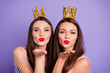 © deagreez - Close up portrait two people beautiful she her models chic ladies hands arms palms send air kisses servants gold crowns head wear summer colorful dresses isolated purple violet bright background