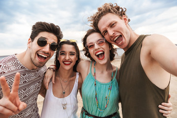 Wall Mural - Group of a cheerful young friends walking at the beach