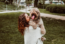.Young And Pretty Woman Spending Free Time With Her Nice Brown Spanish Water Dog In A Park In The Center Of The City Of Madrid. Lifestyle
