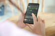 © Oran Tantapakul - Female hand with smartphone trading stock online in coffee shop , Business concept