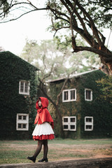 Wall Mural - Portrait young woman with Little Red Riding Hood costume in green tree park