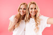 Smiling blonde twins wearing in t-shirts making selfie